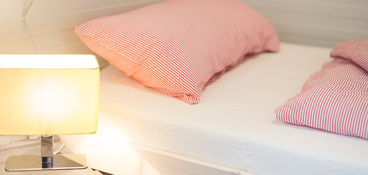 Bett mit Nachttischlampe im Wohncontainer